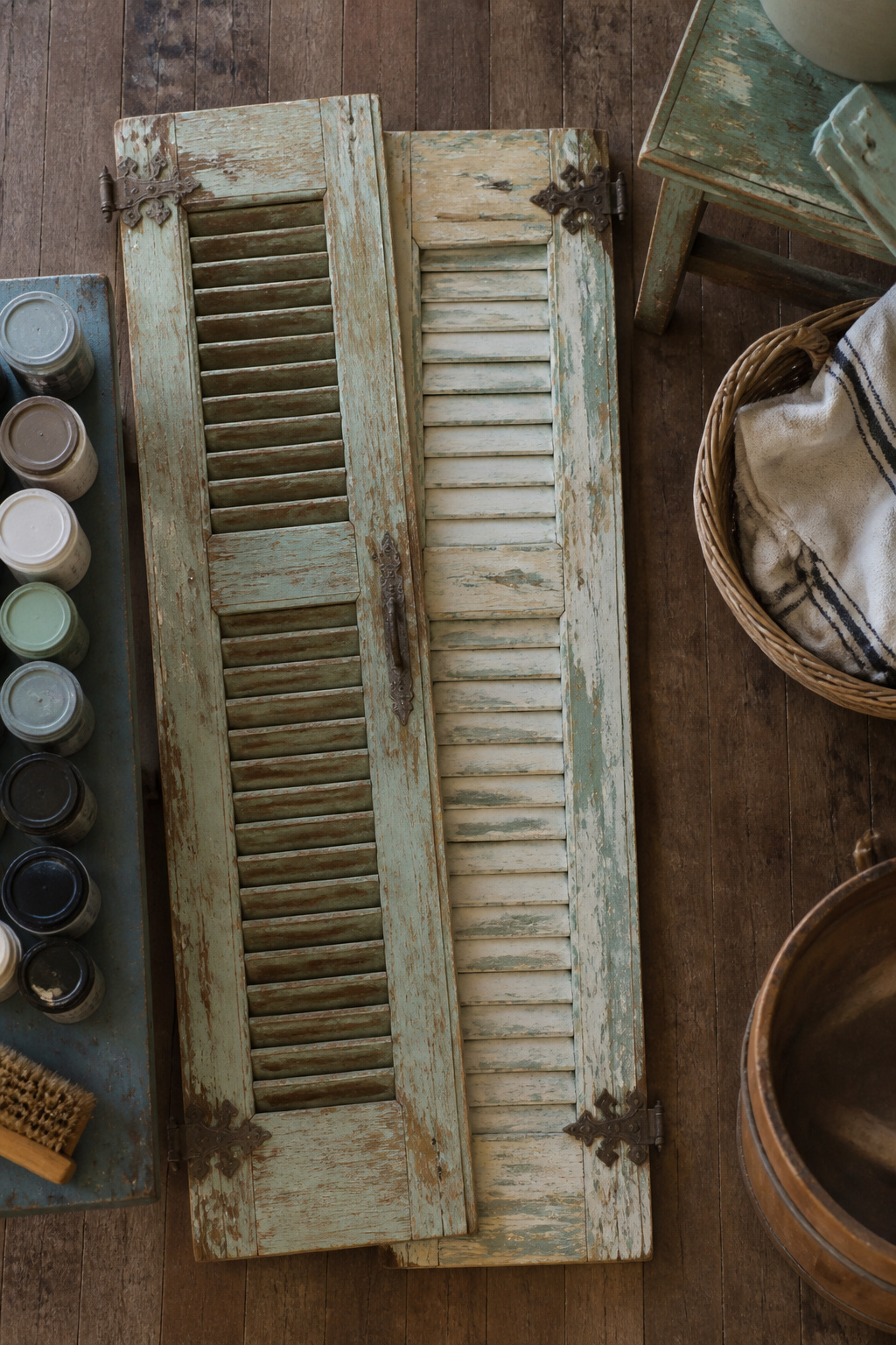 Two old shutters with chipped paint leaning against a wall.