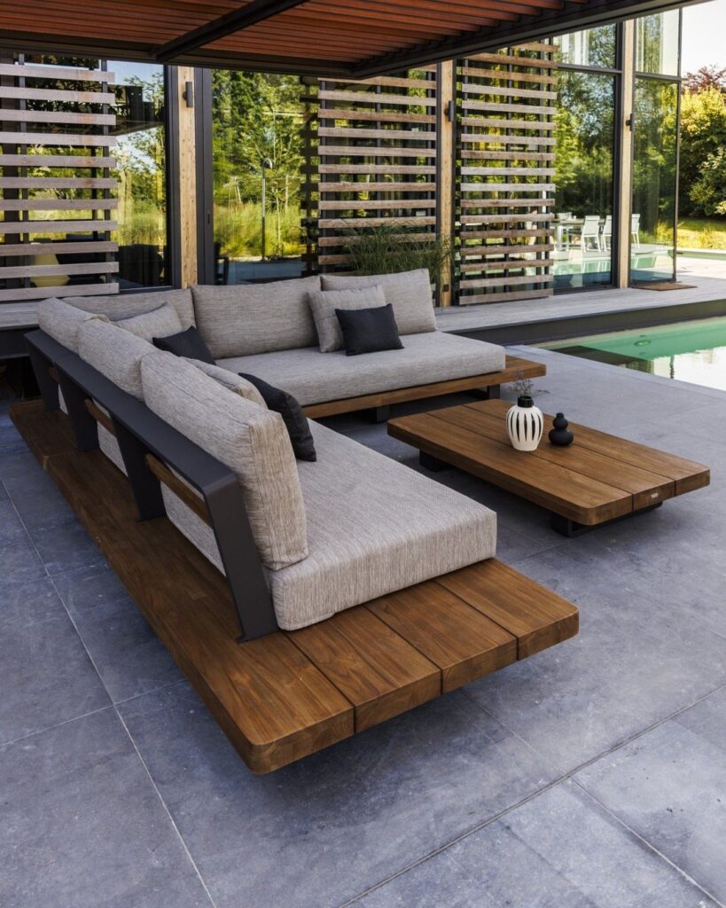 Modern wooden outdoor sofas with grey cushions and a matching coffee table on a patio.